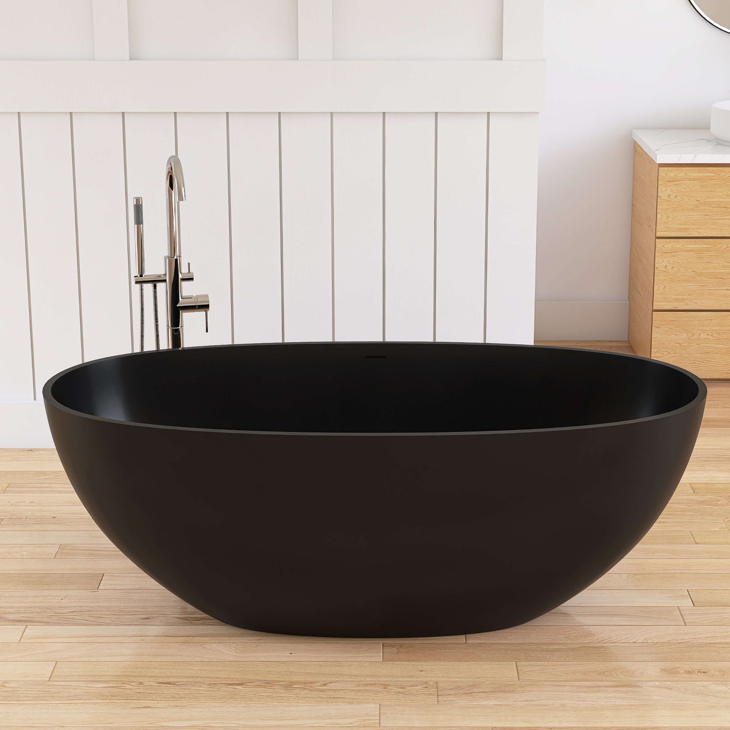 Black solid surface freestanding bathtub in a modern bathroom with wooden floor and white walls.