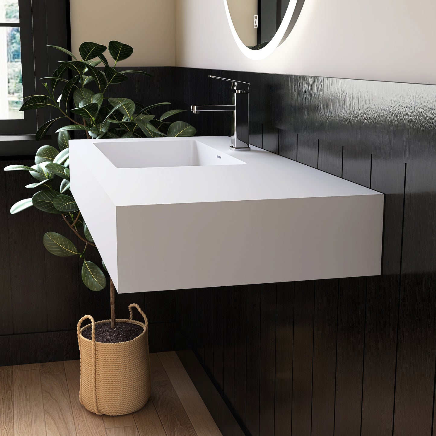 Modern bathroom with a white wall mounted sink, black tiled wall, and a plant.