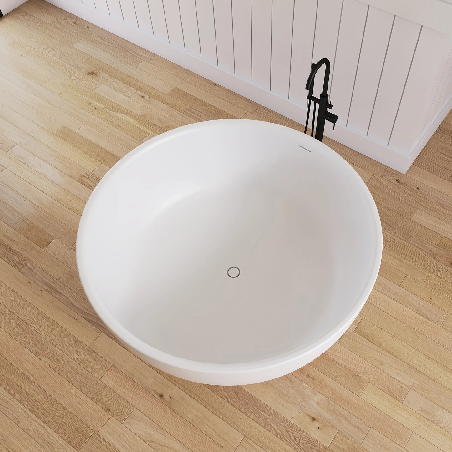 White freestanding bathtub on a wooden floor with a black faucet.