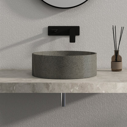 Dark gray solid surface stone sink with black faucet and decorative vase on a light gray countertop.
