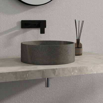 Dark gray solid surface stone sink on a light gray countertop with a textured wall background