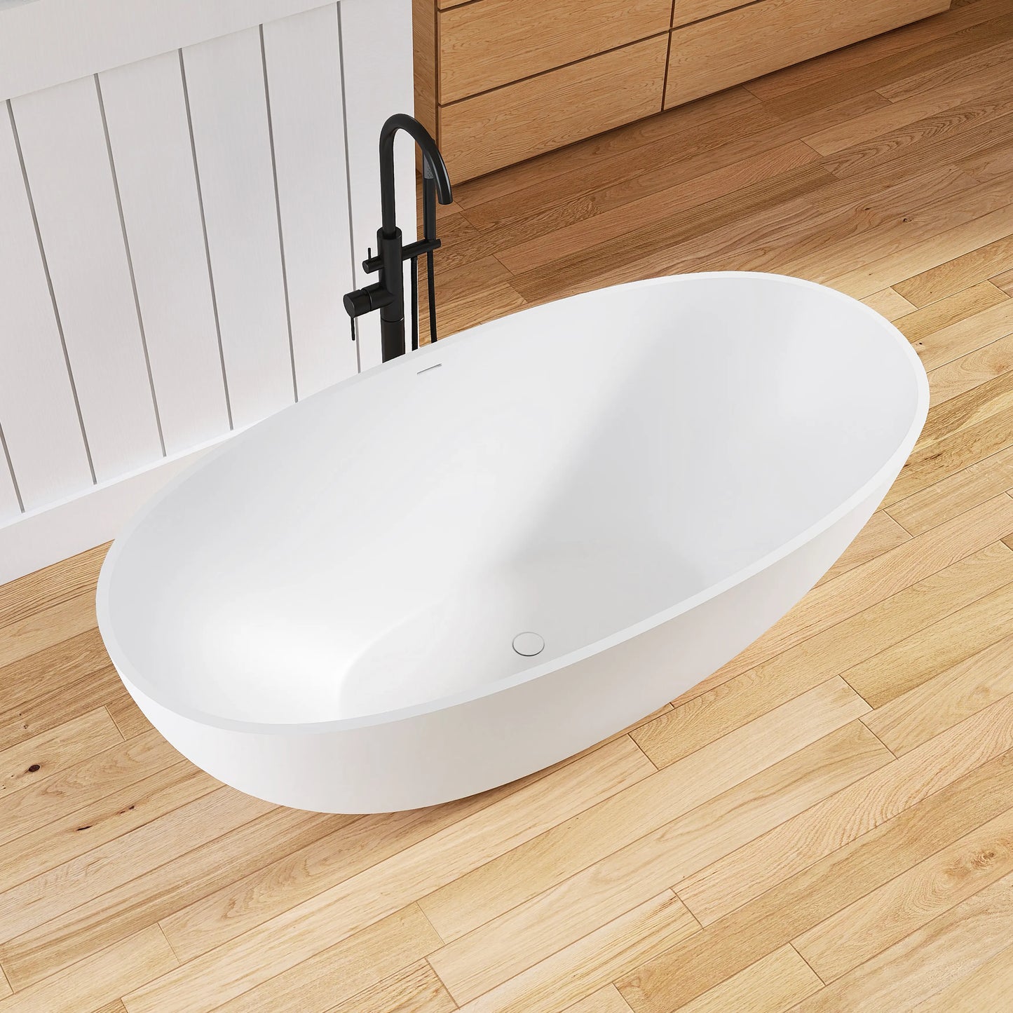 White freestanding bathtub on a wooden floor with a black faucet.