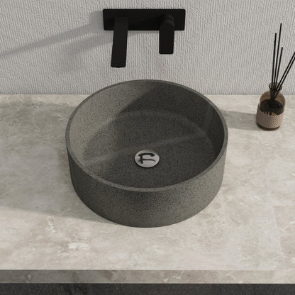 Dark gray solid surface stone sinkon a gray countertop with a black faucet.