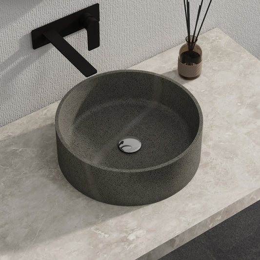 Dark gray solid surface stone sink on a light gray countertop with a black faucet.