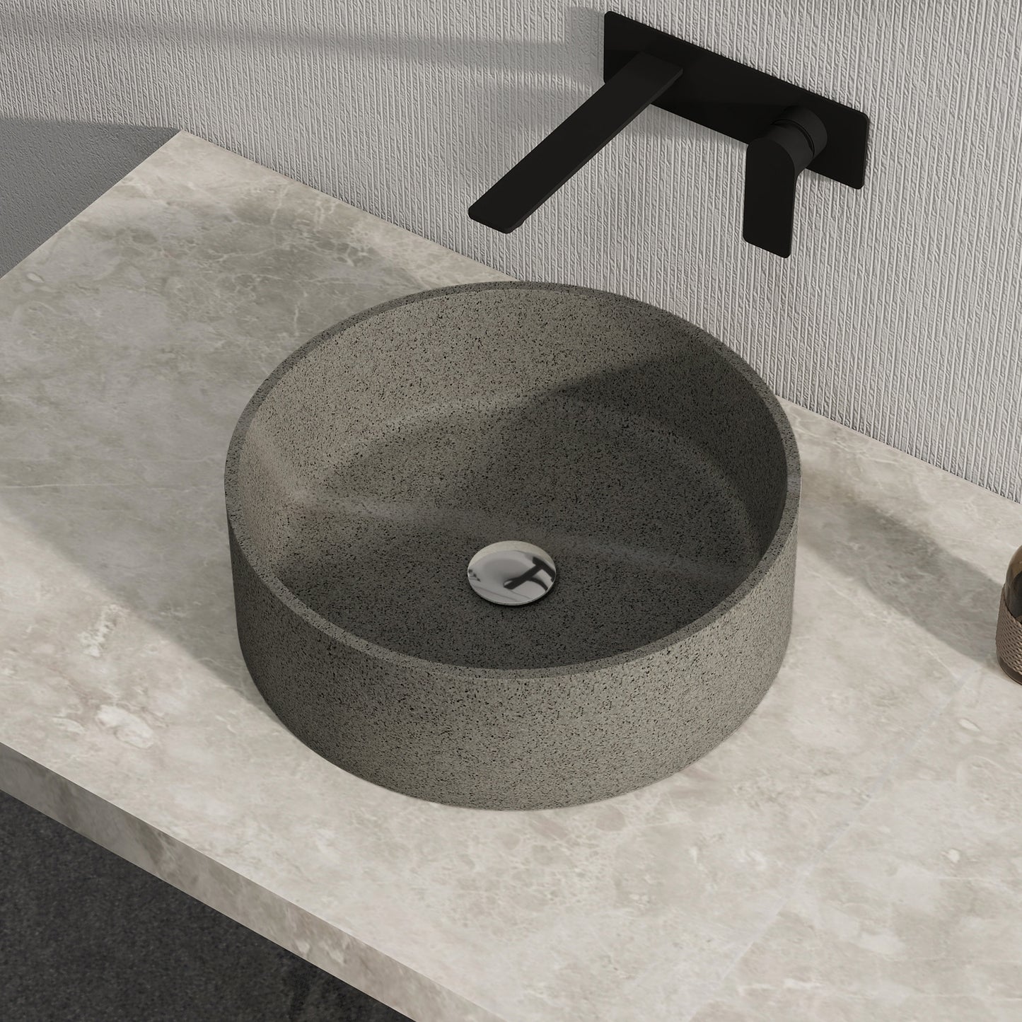 Dark gray solid surface stone sink on a stone countertop with a black faucet.
