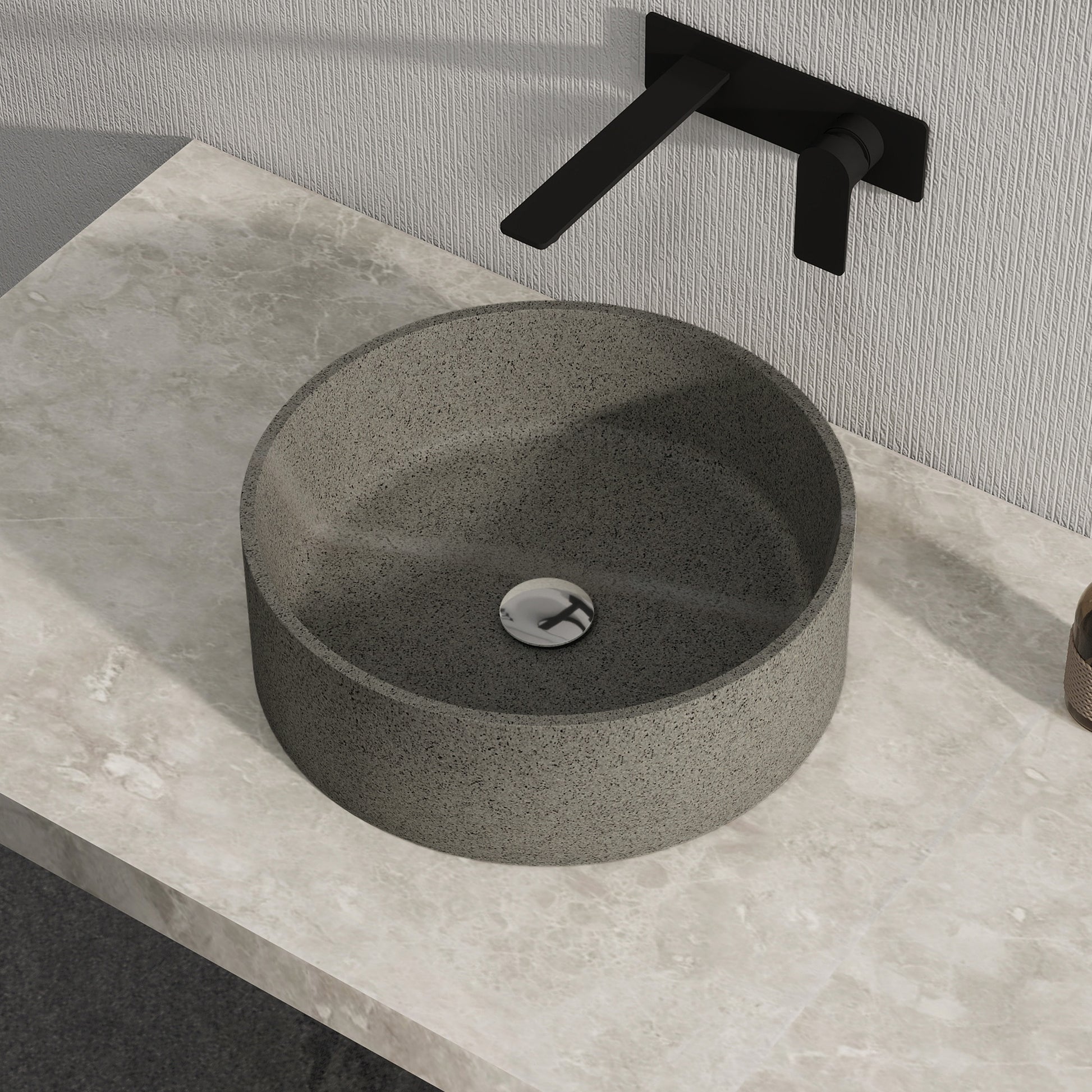 Dark gray solid surface stone sink on a stone countertop with a black faucet.