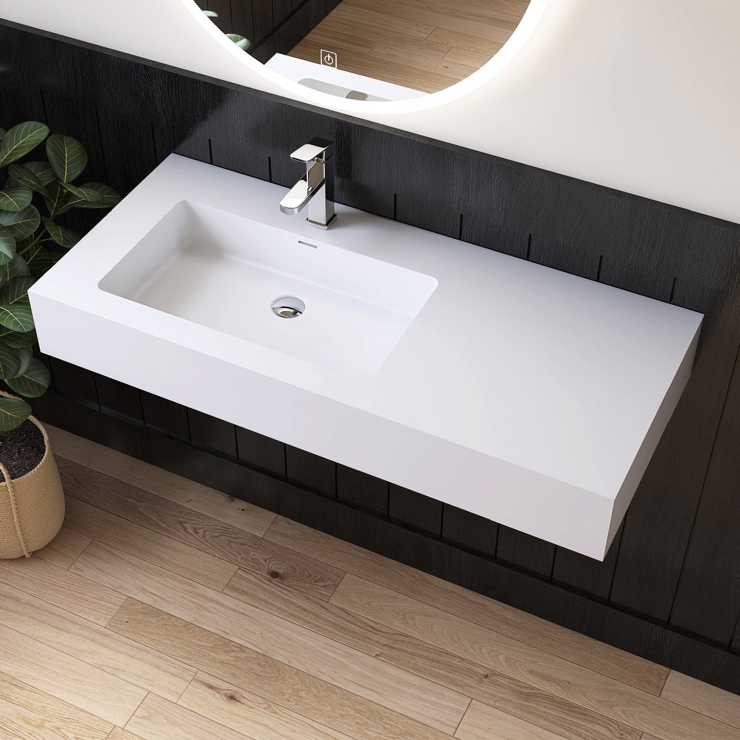 White wall mounted sink on a dark wooden wall with a mirror above it