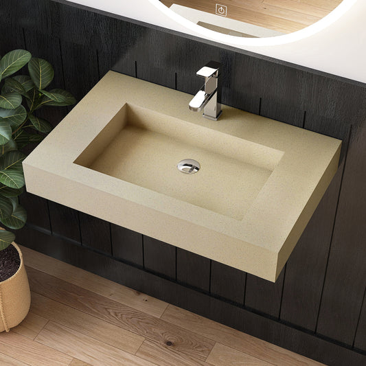 Beige wall mounted sink on a dark wooden vanity with a plant to the left.