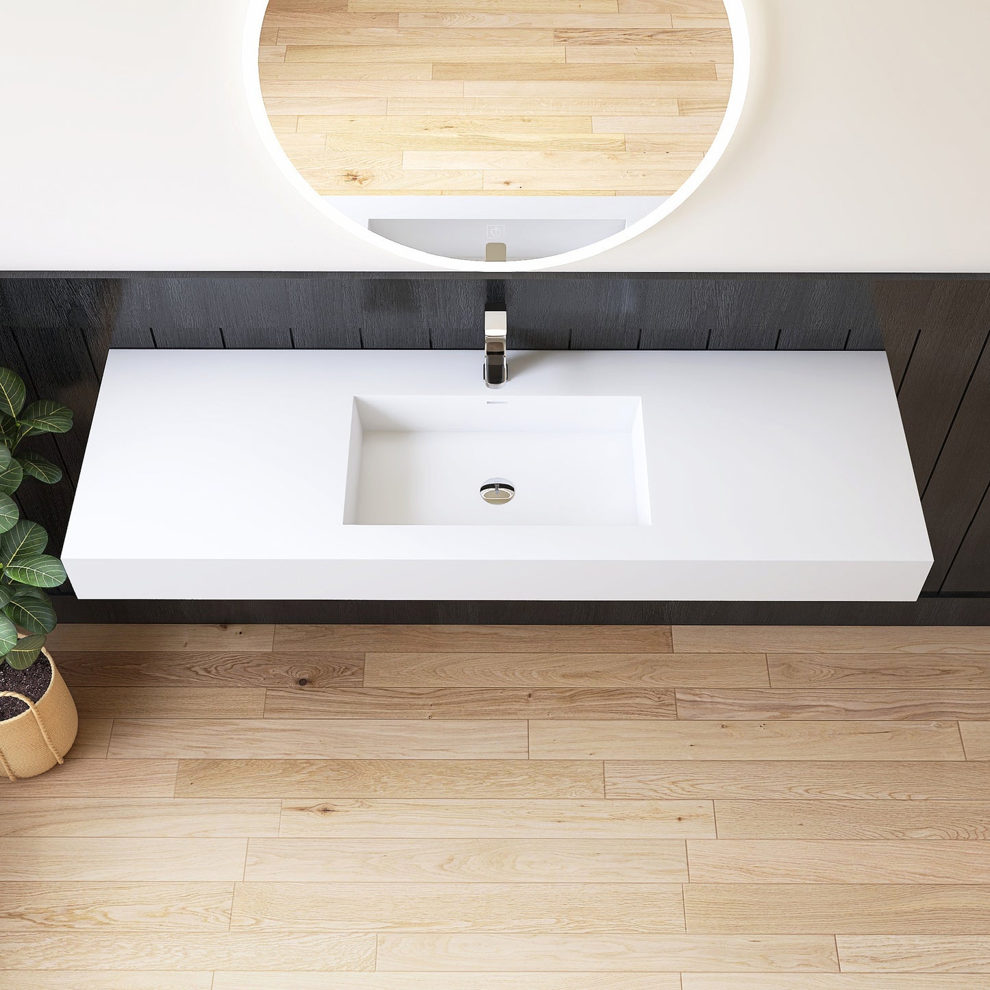 Modern bathroom vanity with white long sink and round mirror on a wooden floor.