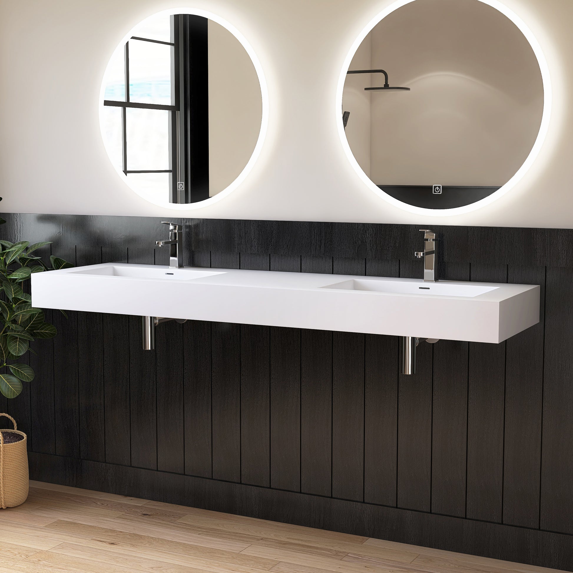 Bathroom with a white double wall-mounted sink, black wall panels, and round illuminated mirrors.