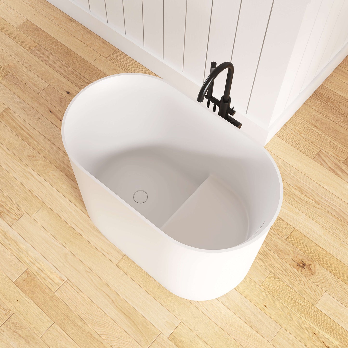 White freestanding bathtub on a wooden floor with a black faucet.