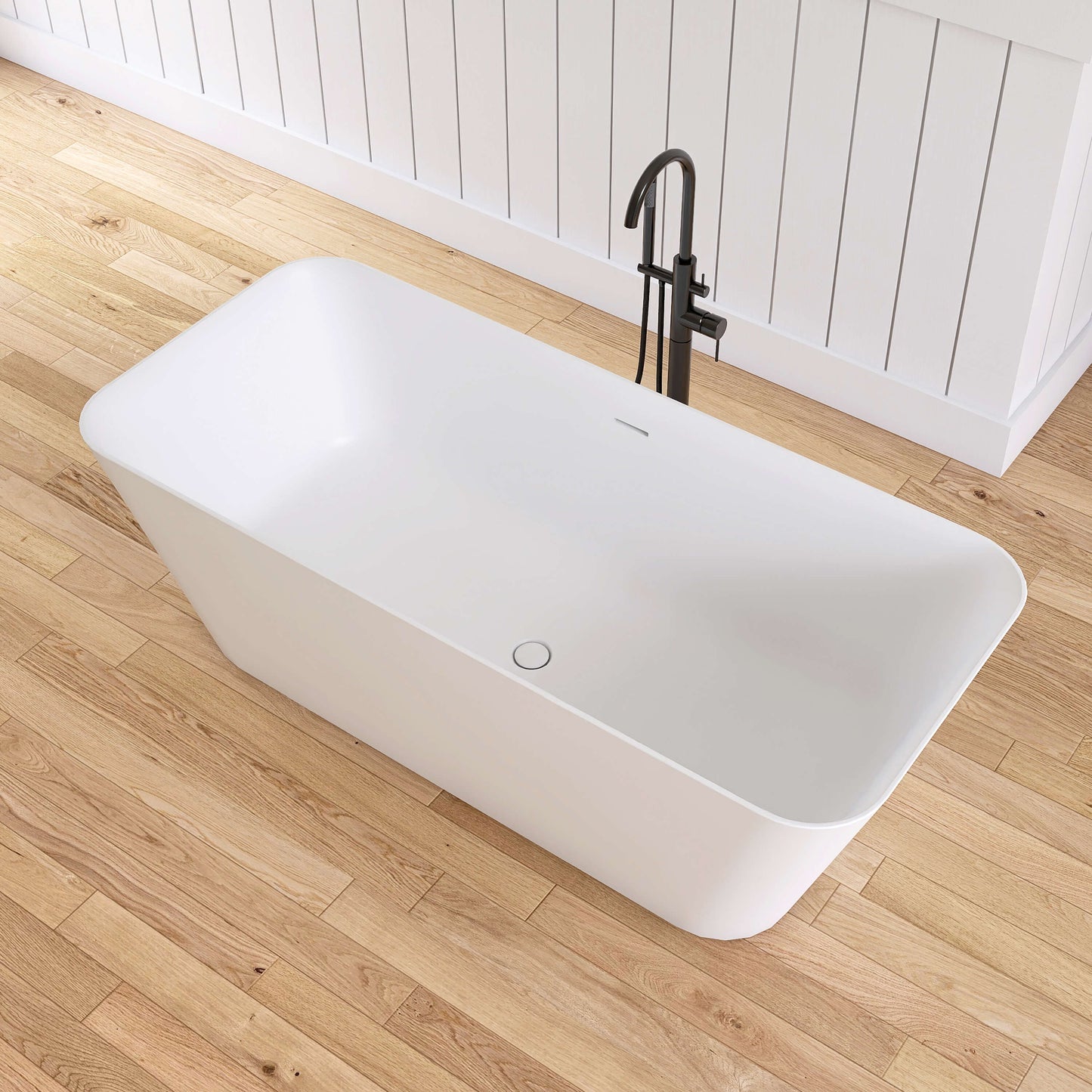 White freestanding bathtub with black faucet on a wooden floor