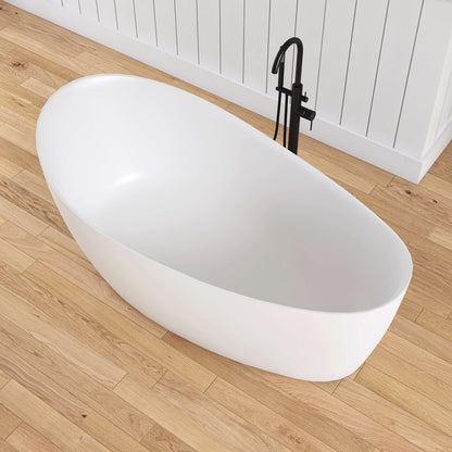 White freestanding bathtub on a wooden floor with a black faucet.