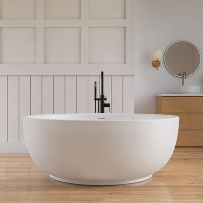 Modern white freestanding bathtub in a bathroom with wooden flooring and wall.