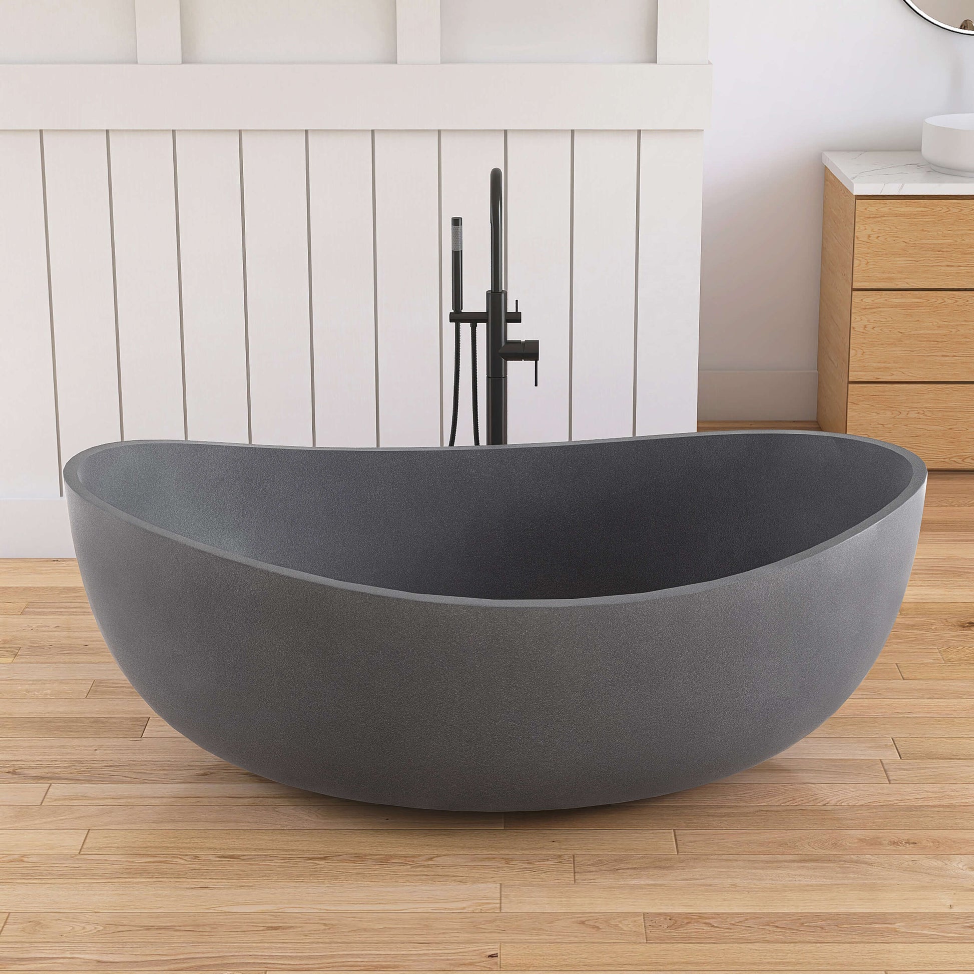 Gray freestanding bathtub in a bathroom with wooden floor and white wall.
