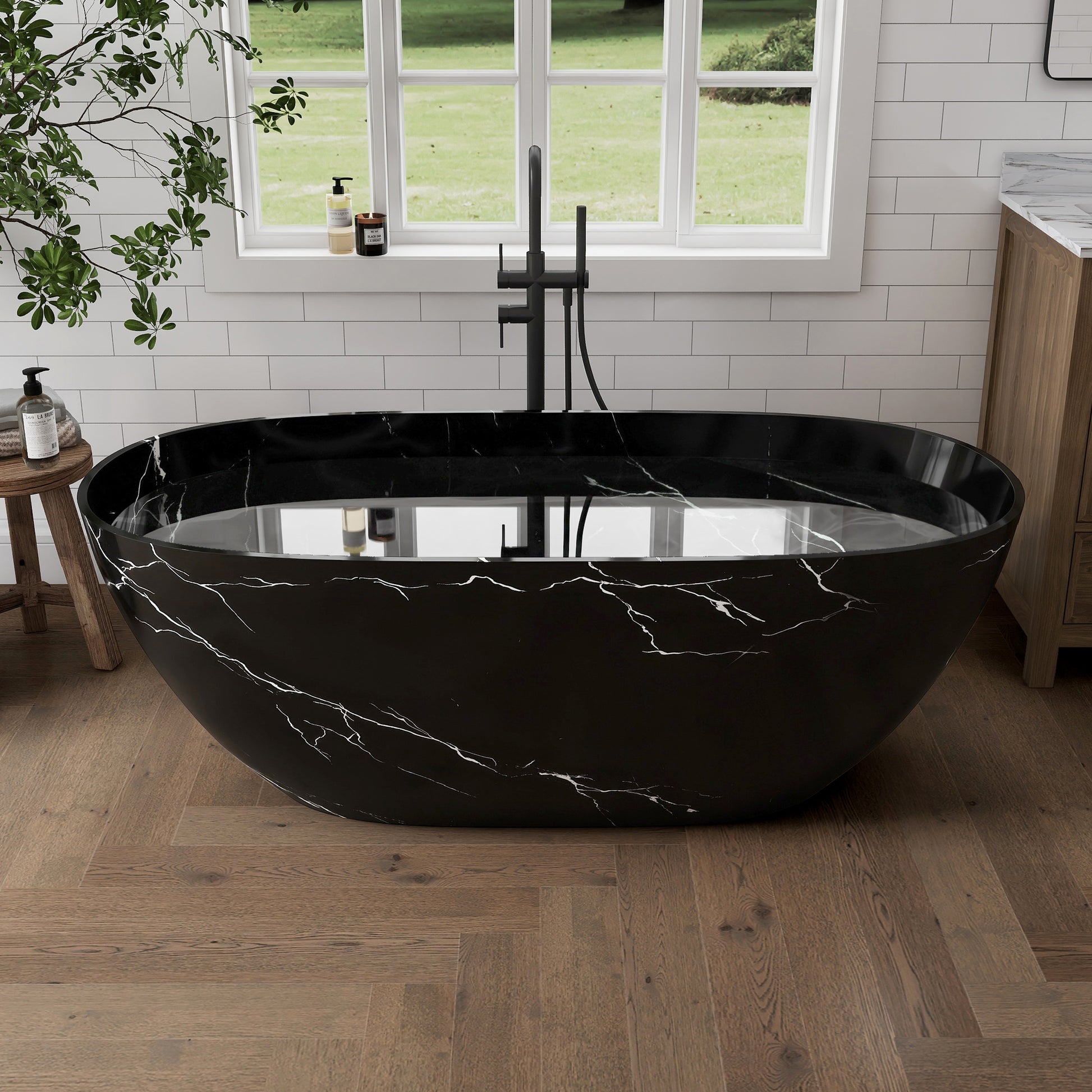 Black marble-patterned bathtub in a bathroom with a window and plant in the background