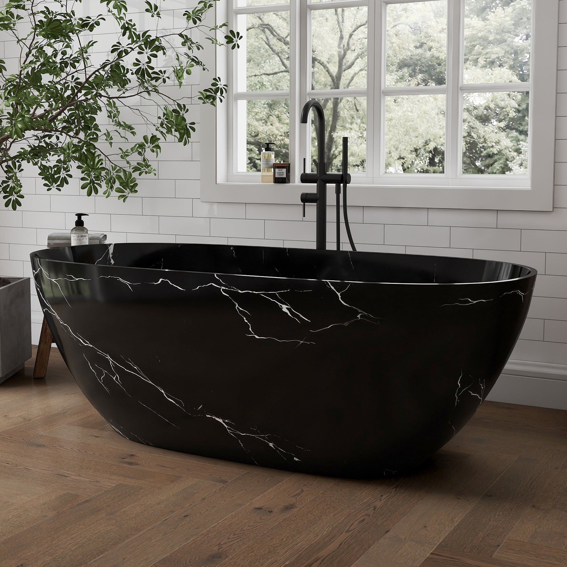 Black marble-patterned bathtub in a bathroom with a window and plant