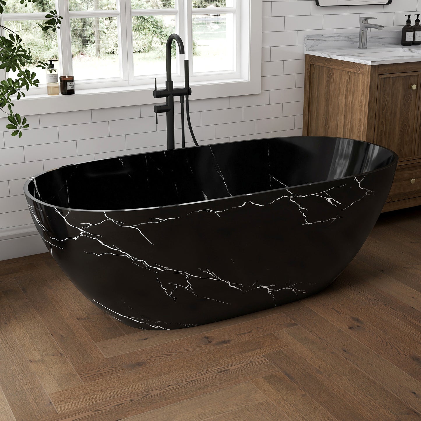 Black marble-patterned freestanding bathtub in a bathroom with wooden floor and window.