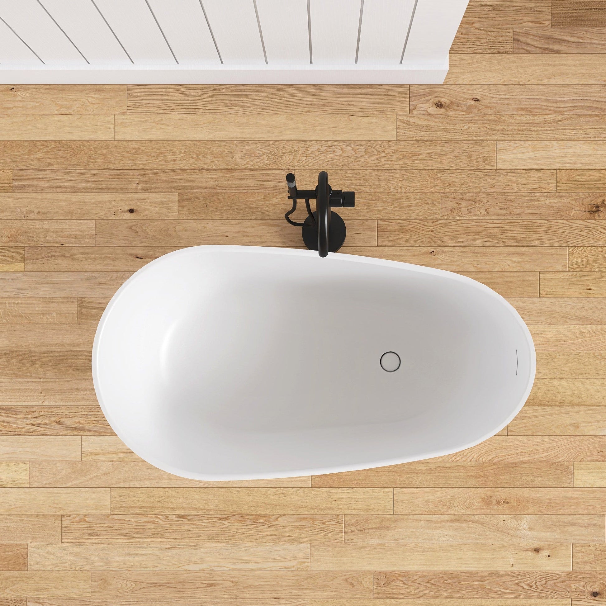 White freestanding bathtub on a wooden floor with a black faucet.