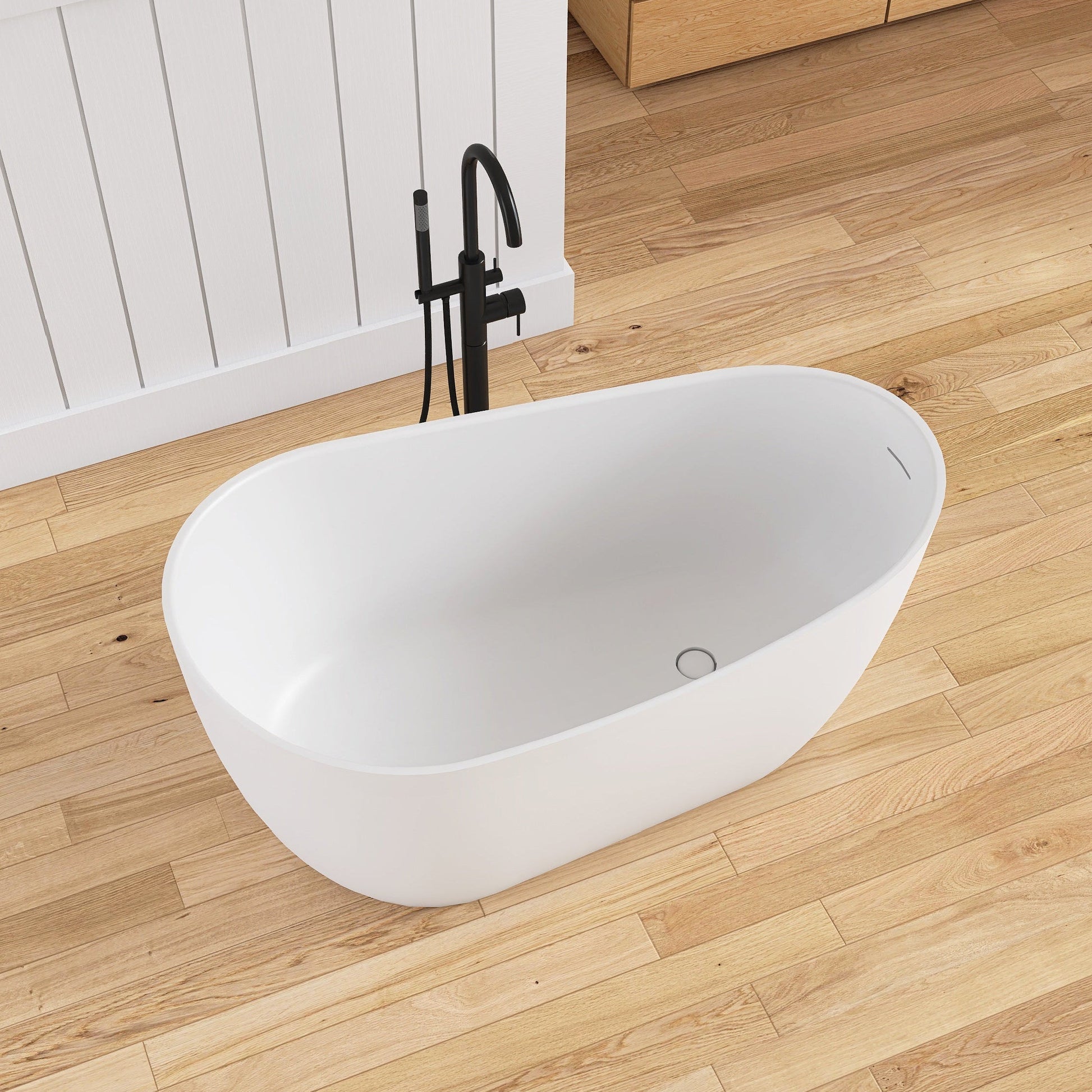 White freestanding bathtub on a wooden floor with a white wall in the background