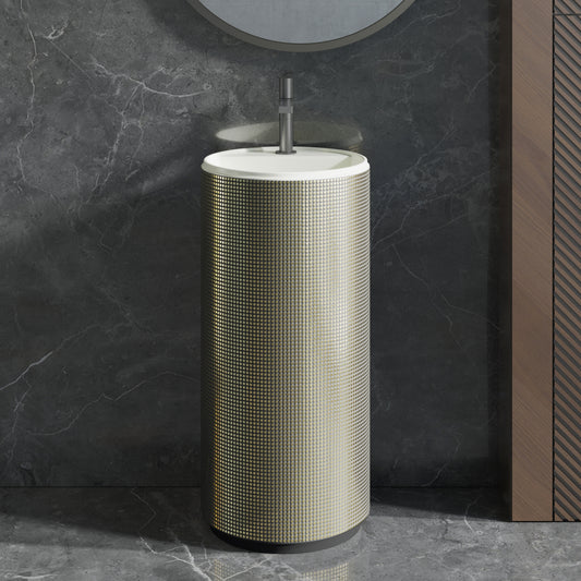 Cylindrical freestanding sink with Antique Gold Electroplated Grid against a dark marble wall.